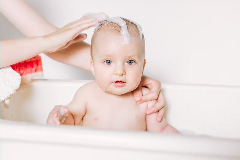Mother is applying shampoo on baby's hair
