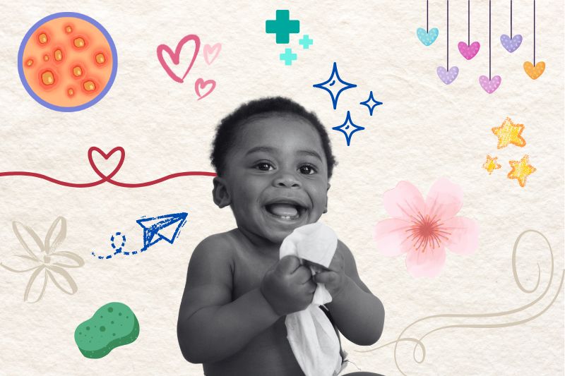 A happy baby is holding a wipe in his hands