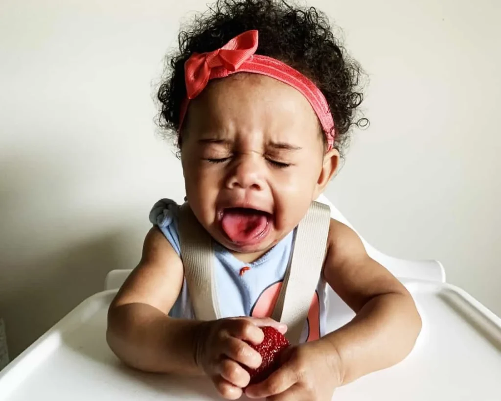 a baby girl is making faces while trying new taste for the fist time