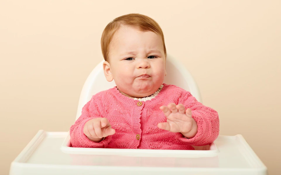 Baby making faces while eating.