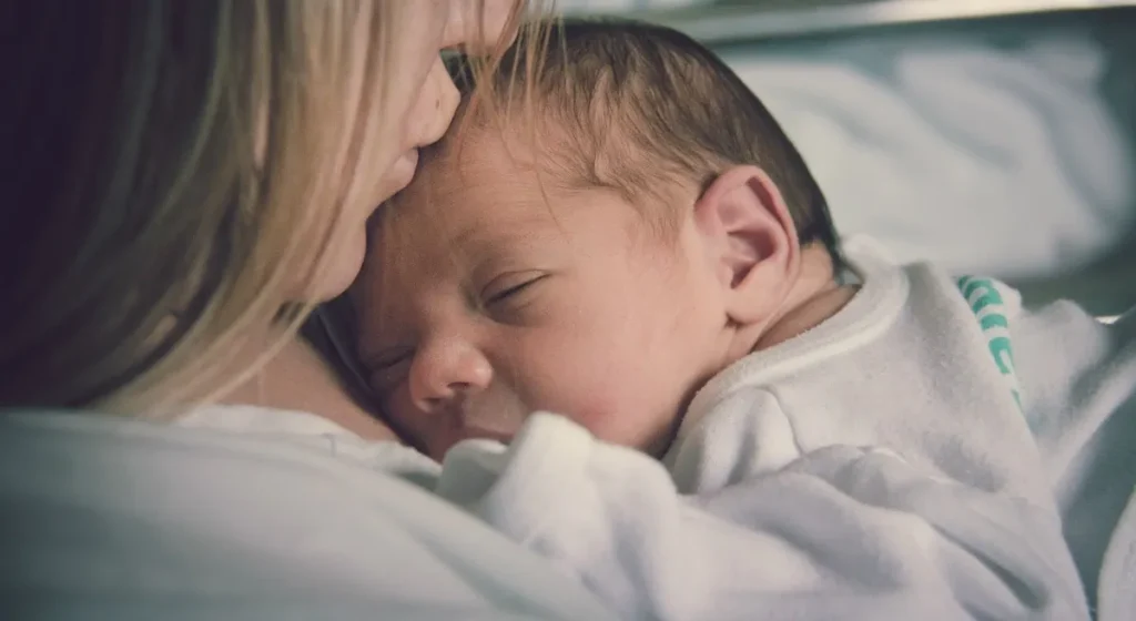 A mother kisses her baby on the forehead with love and compassion.