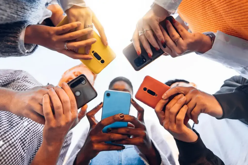 A bunch of teens using phones curiously.